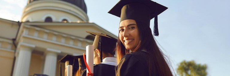 Absolventin hält ihre Abschlussurkunde in der Hand und lächelt